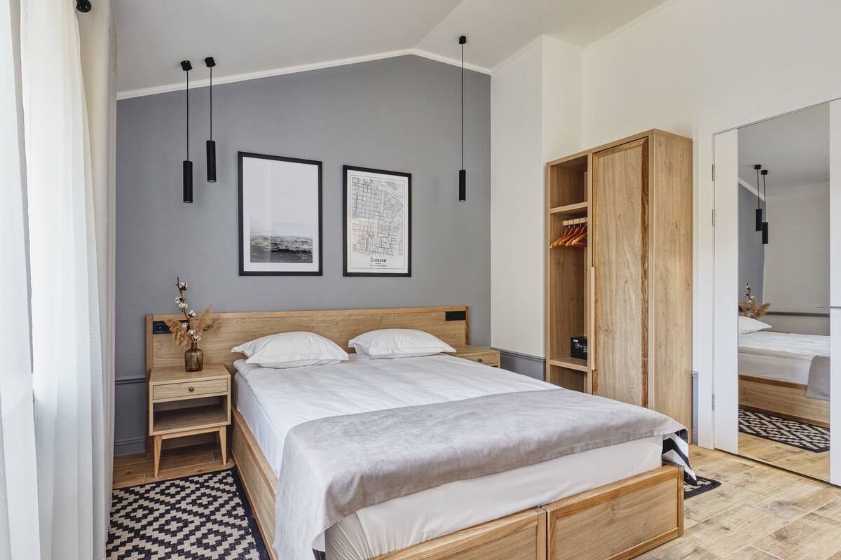 Ein modernes Schlafzimmer mit einem Holzbett, einem Nachttisch, einem Kleiderschrank und zwei gerahmten Bildern an der Wand.