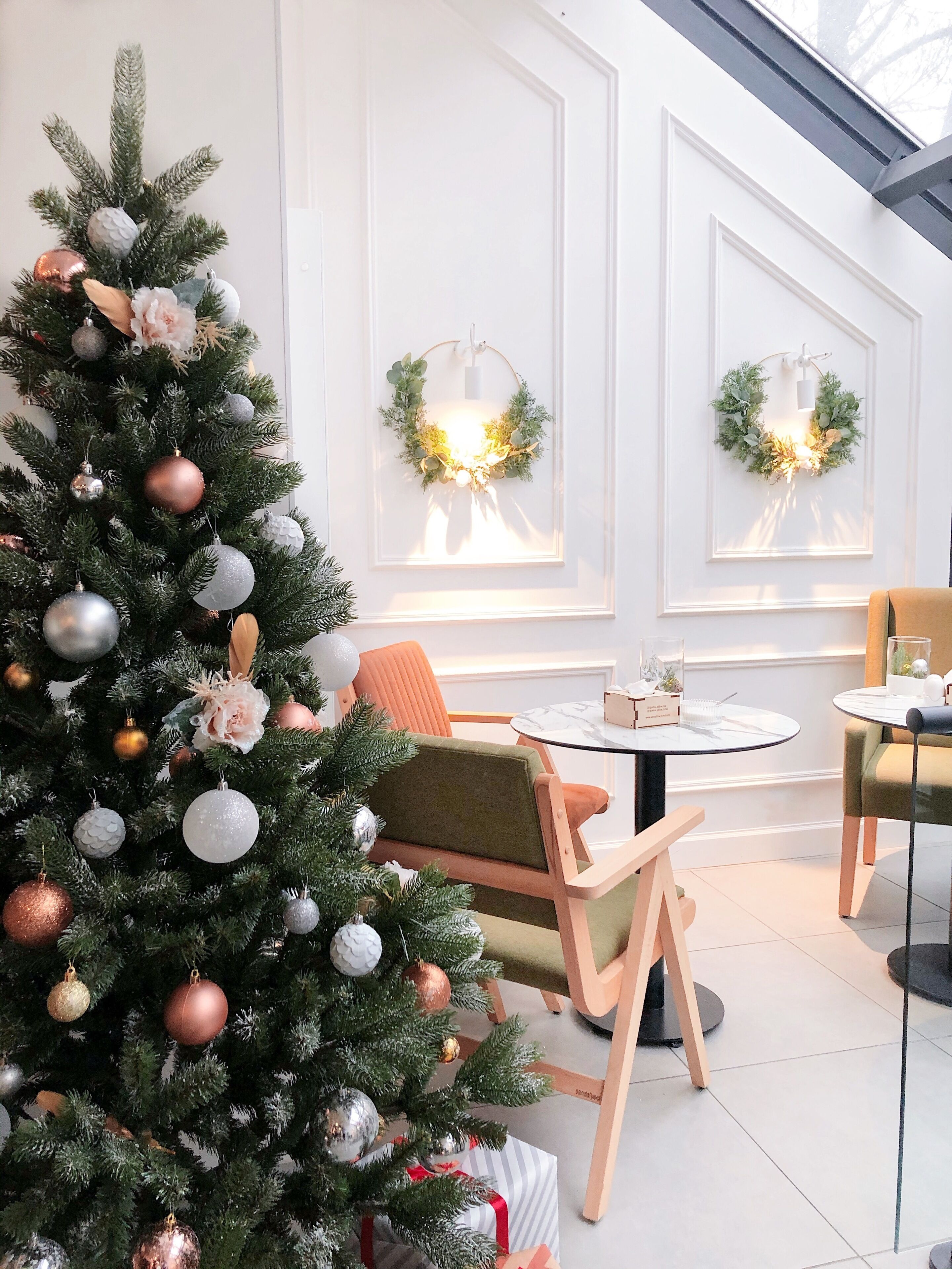 Un moderno vestíbulo de hotel con un árbol de Navidad, zonas de estar y apliques decorativos.