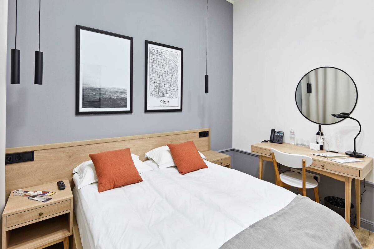 Ein Hotelzimmer mit einem Bett, einem Schreibtisch mit Stuhl, einer Schreibtischlampe, einem Telefon und einem Spiegel.