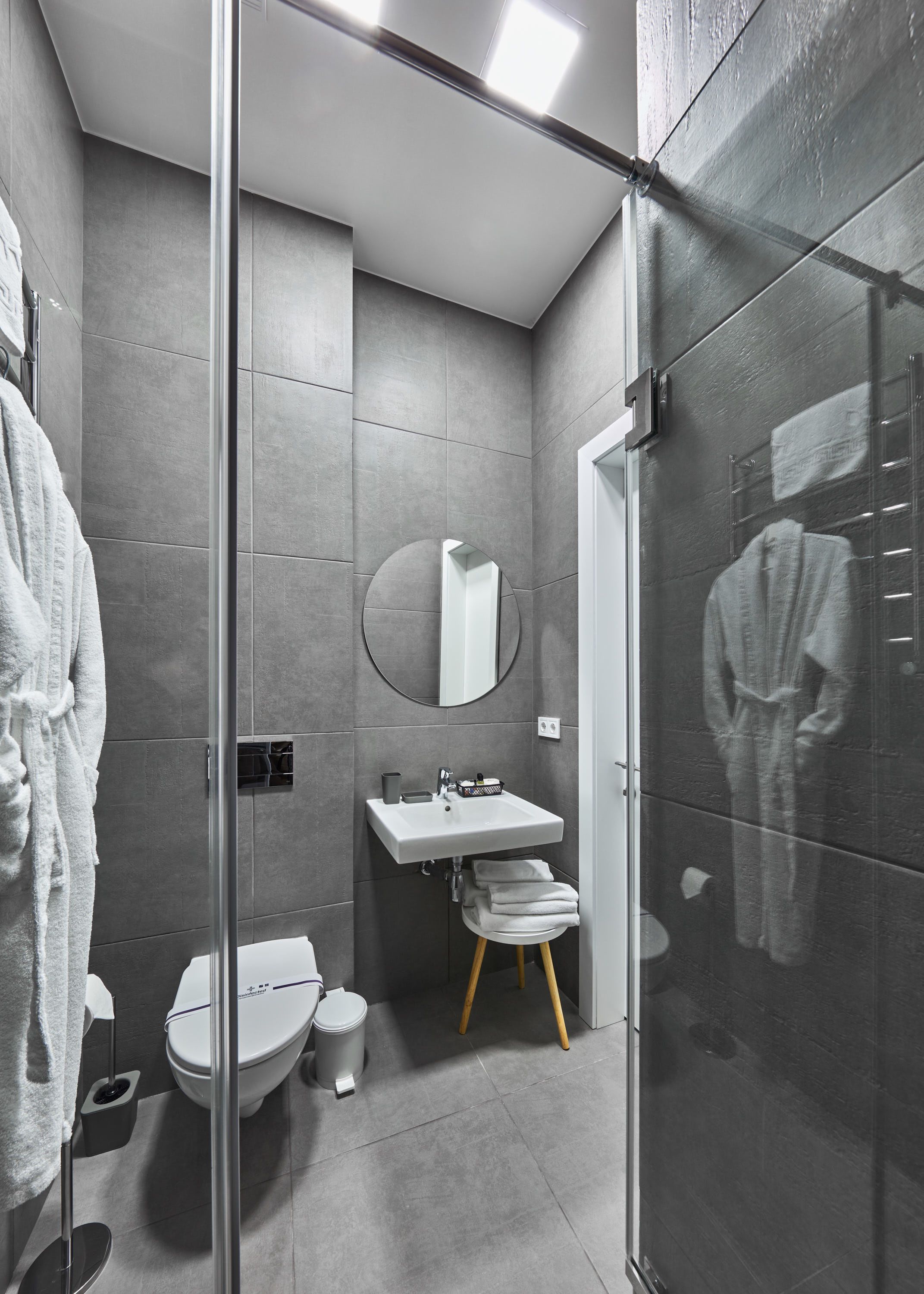 A modern bathroom with a glass shower enclosure, a white sink, and a toilet.