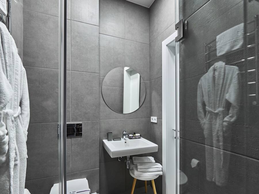 A modern bathroom with a glass shower enclosure, a white sink, and a toilet.