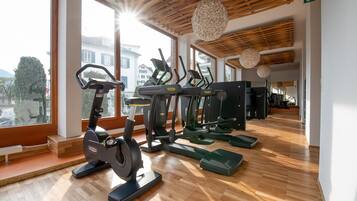 Una palestra con attrezzature per esercizi, ampie finestre e un soffitto in legno.