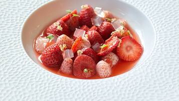 Un tazón blanco lleno de fresas en rodajas y cubitos de hielo sobre una superficie blanca con textura.