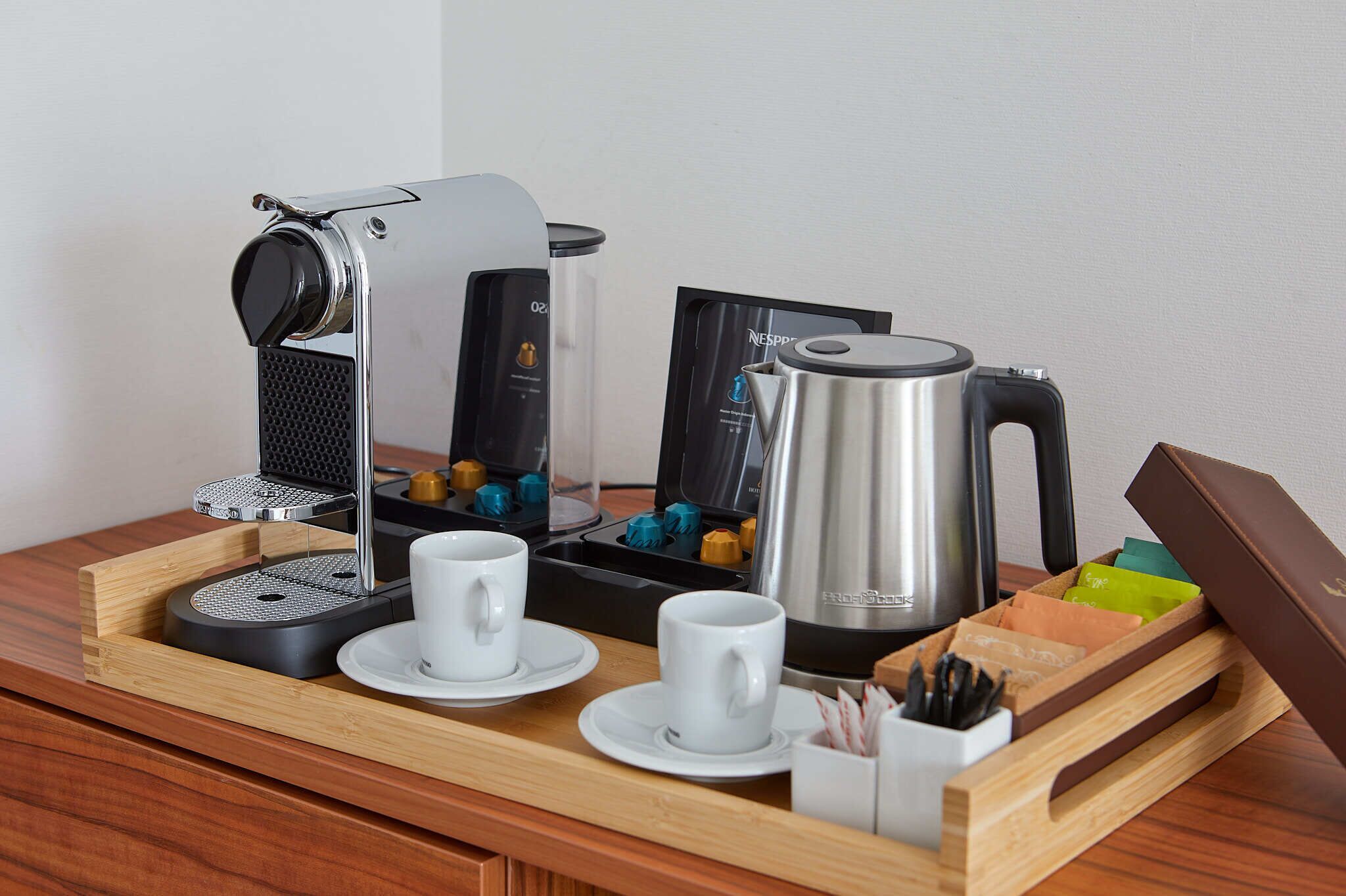 Una estación de café con cafetera, hervidor y tazas sobre una bandeja.