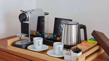 Una estación de café con cafetera, hervidor y tazas sobre una bandeja.
