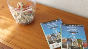 Two travel maps and a glass container with seashells and a red string. - Leolù Guesthouse and breakfast (Alghero)