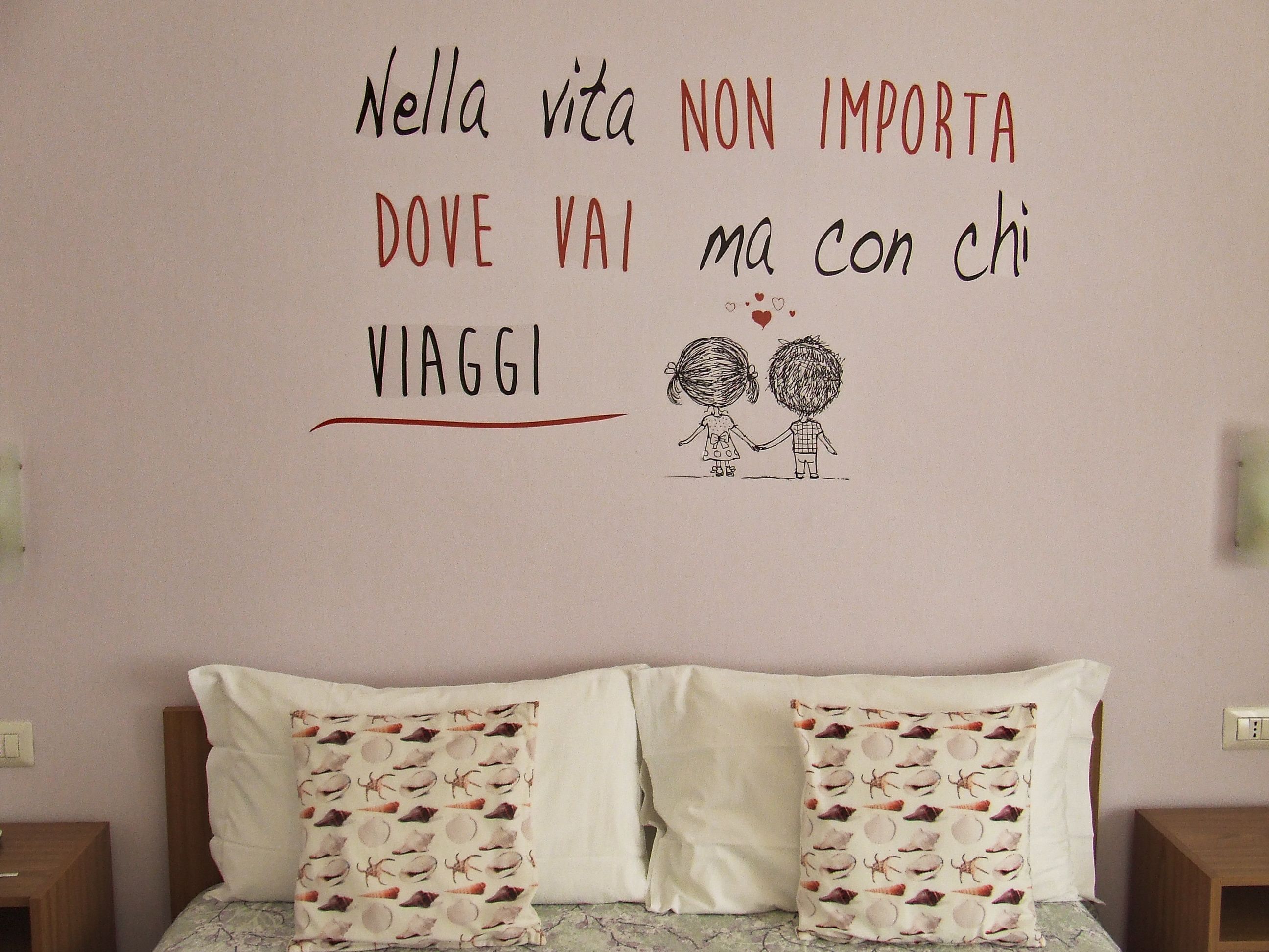 A bedroom with a bed, pillows, and a wall with a message and a drawing of two people holding hands.