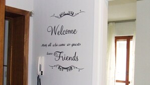A wall with a welcome sign that reads "Welcome May all who came as guests leave as Friends" with decorative flourishes. - Leolù Guesthouse and breakfast (Alghero)
