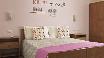 Quarto com cama, duas mesas de cabeceira, guarda-roupa e parede com uma frase motivacional.