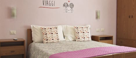 A bedroom with a bed, two bedside tables, a wardrobe, and a wall with a motivational quote.