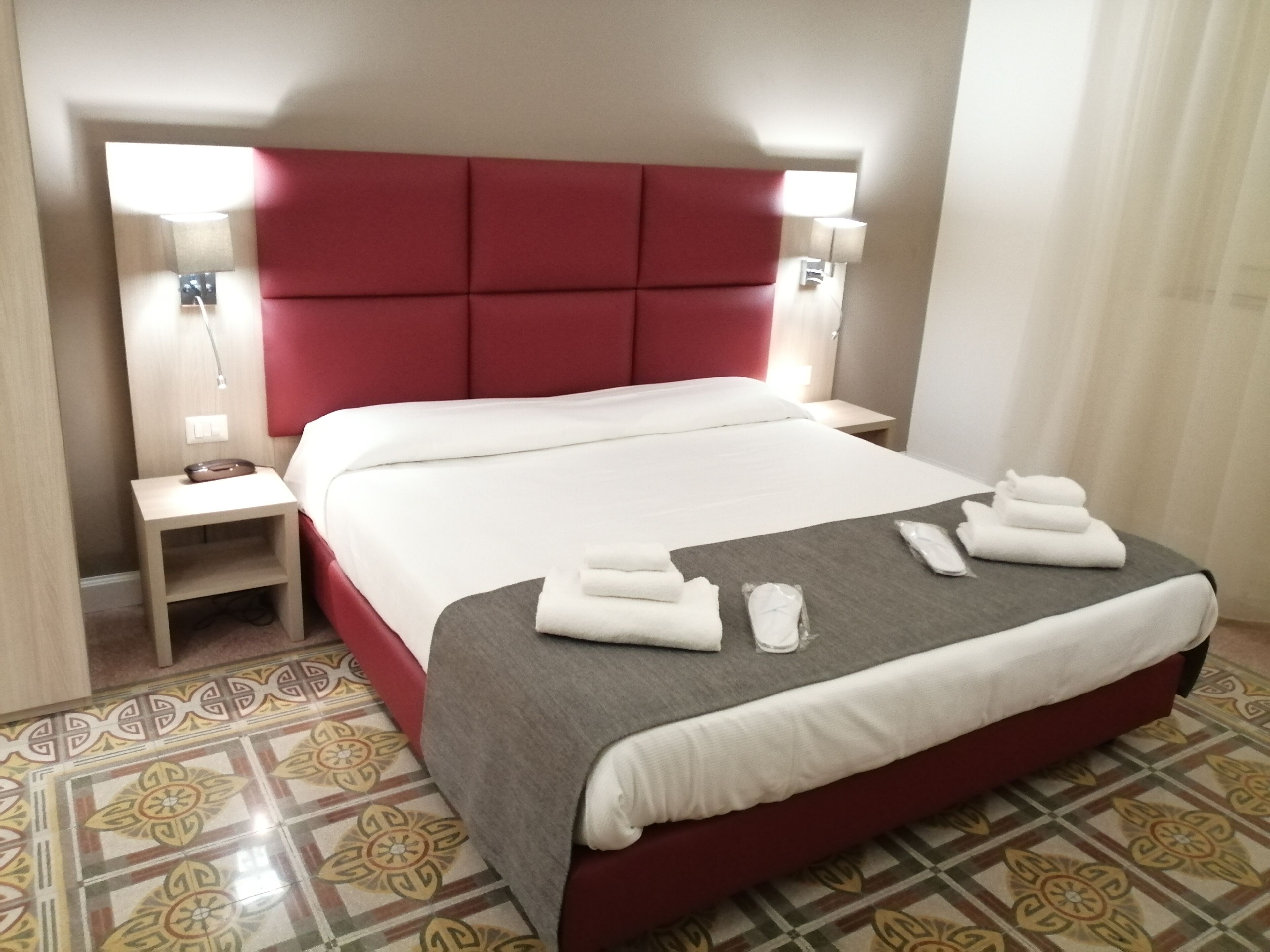 Ein Hotelzimmer mit einem großen Bett, einem Nachttisch und einer Lampe.