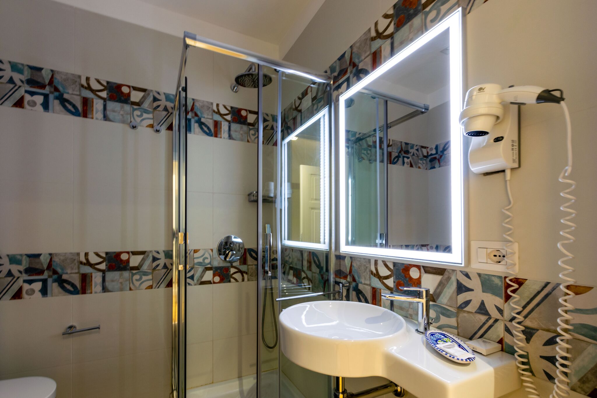 A modern bathroom with a glass-enclosed shower, a white sink, and a large mirror.
