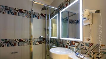 A modern bathroom with a glass-enclosed shower, a white sink, and a large mirror.