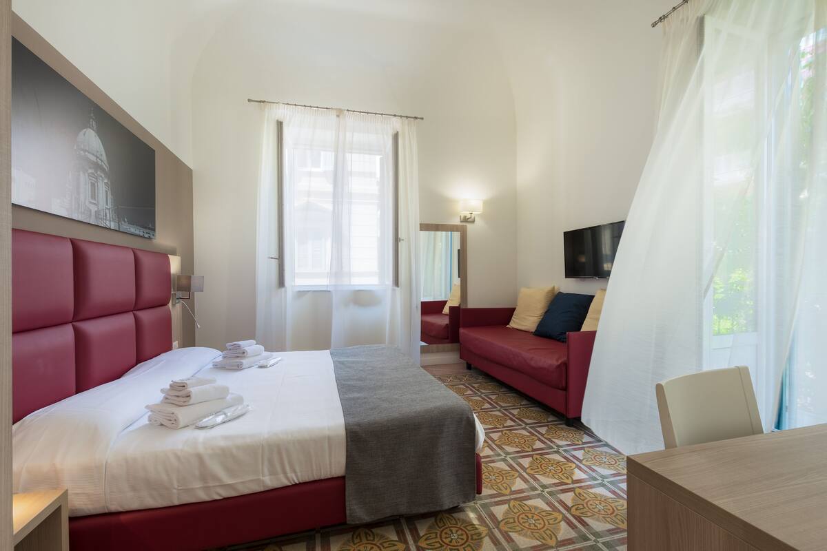 Ett hotellrum med en stor säng, en soffa, en tv och ett matbord.
