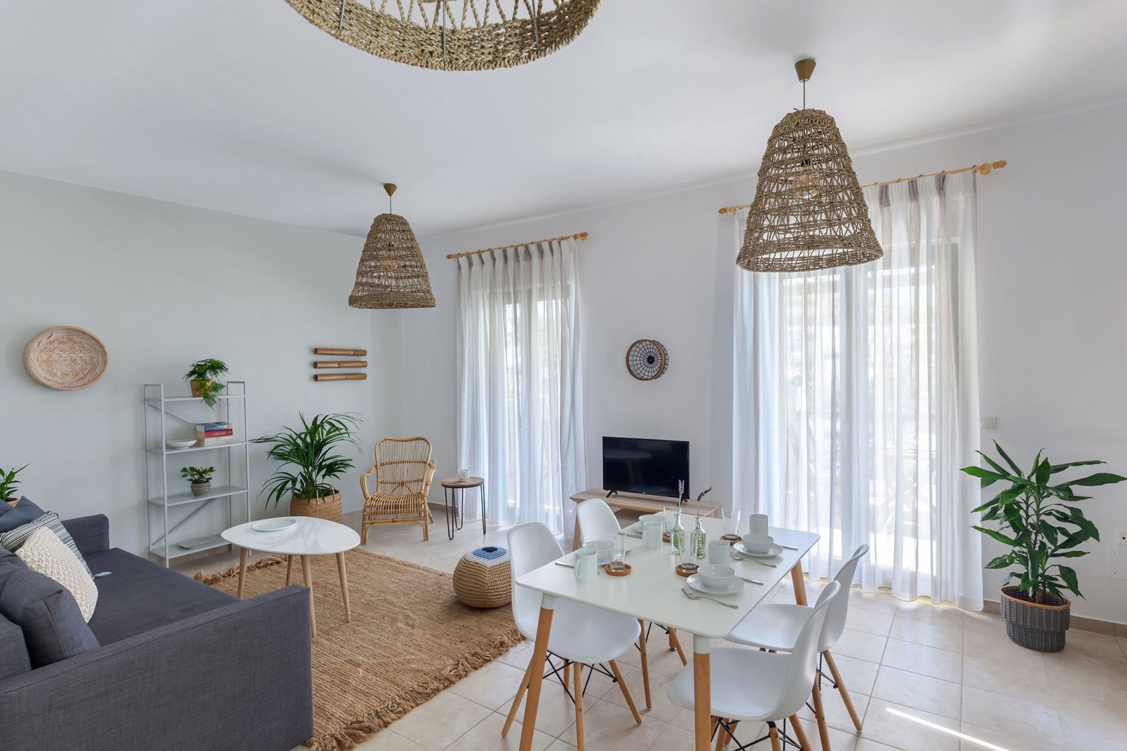 A modern living room with a sofa, dining table, and chairs, a TV, and a bookshelf.