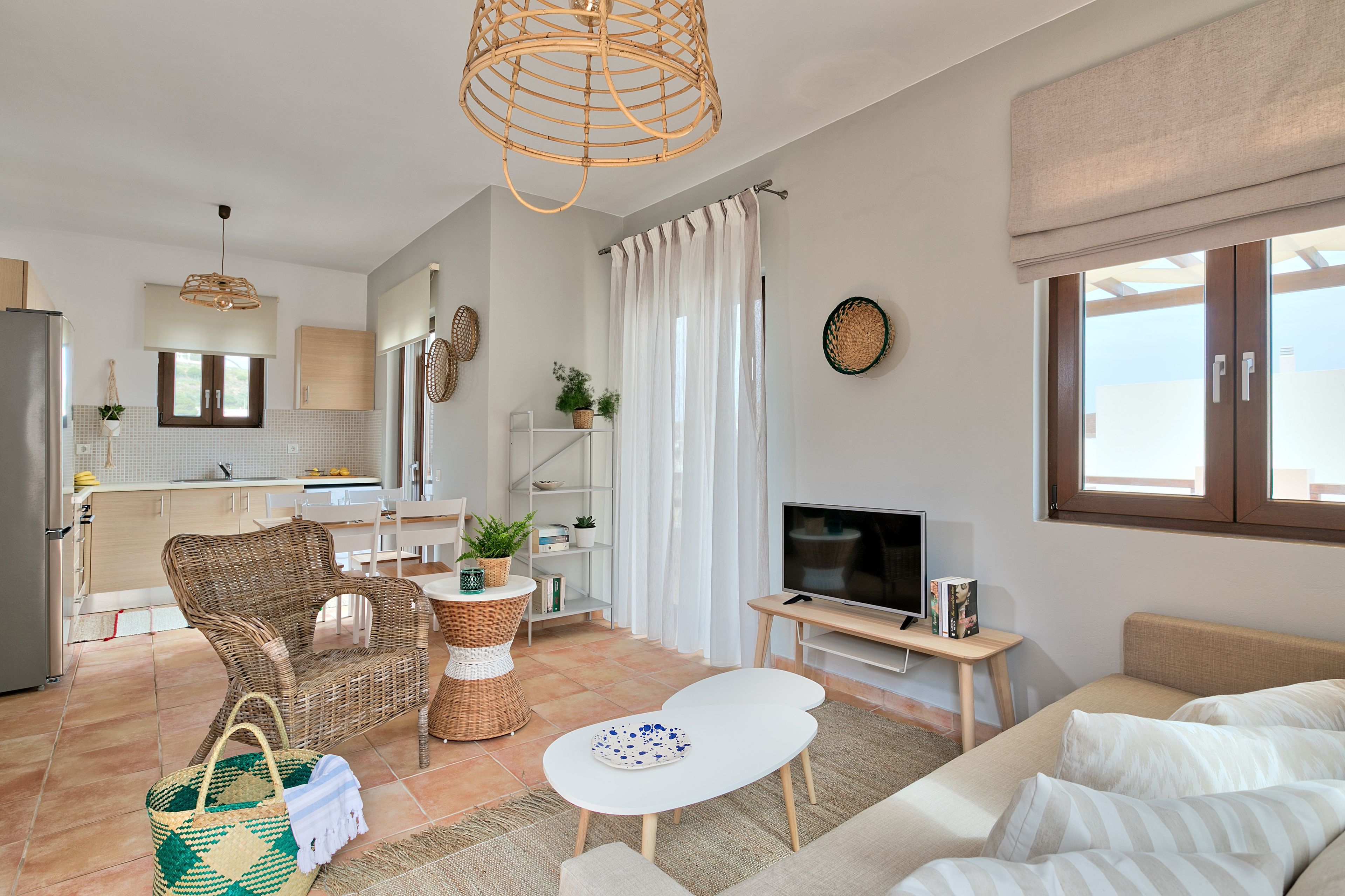 A modern living room with a sofa, a dining table, a TV, and a kitchen in the background.
