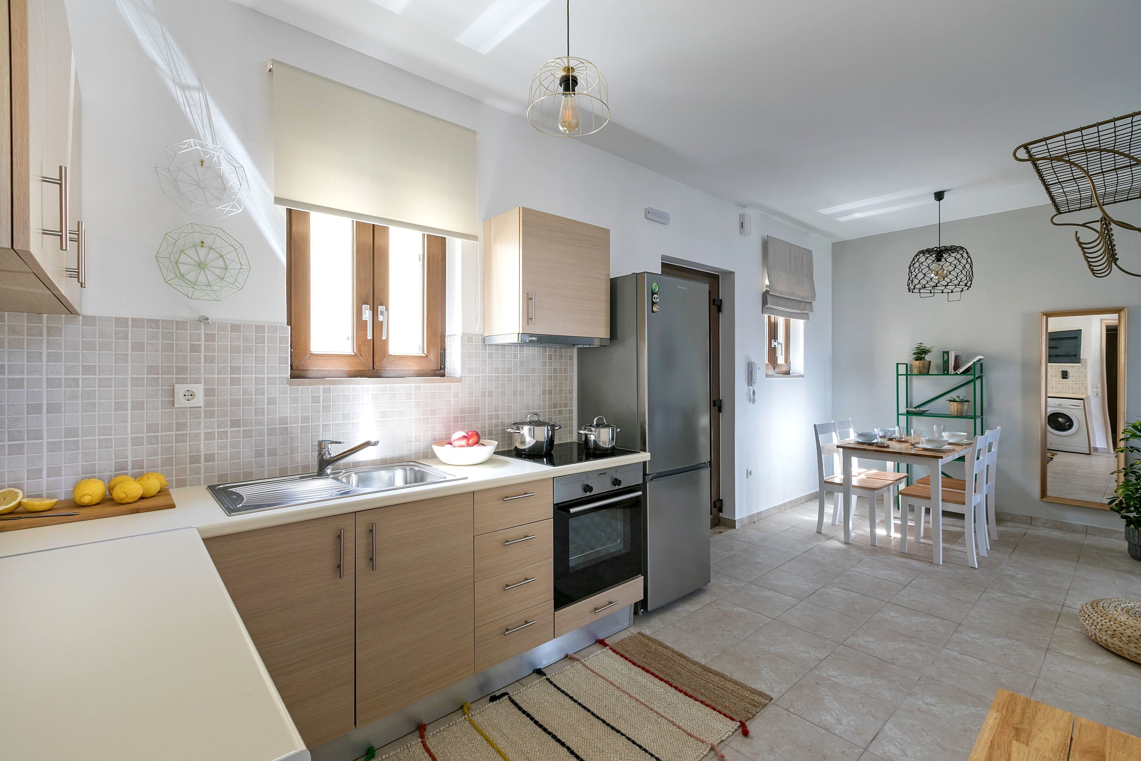 Una cocina moderna con armarios de madera, un refrigerador de acero inoxidable y un comedor con mesa y sillas.