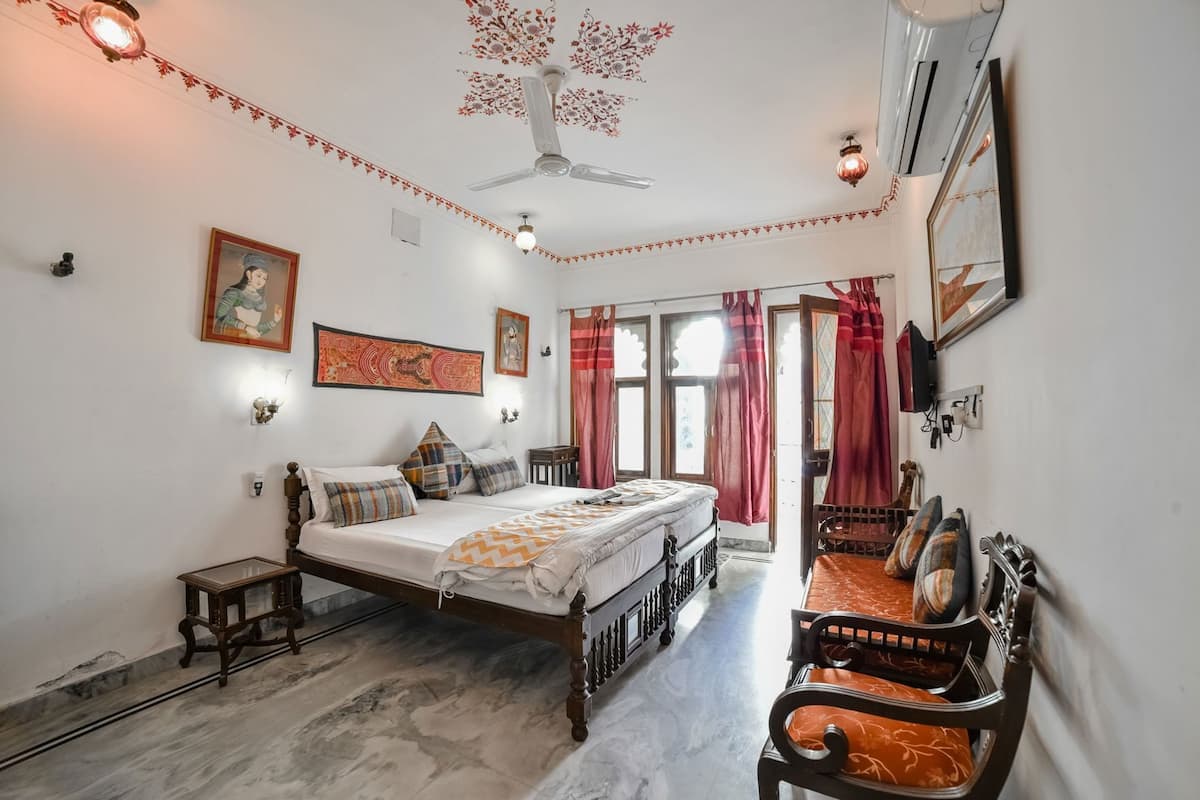 A bedroom with a bed, a nightstand, a chair, a ceiling fan, and a wall-mounted TV.