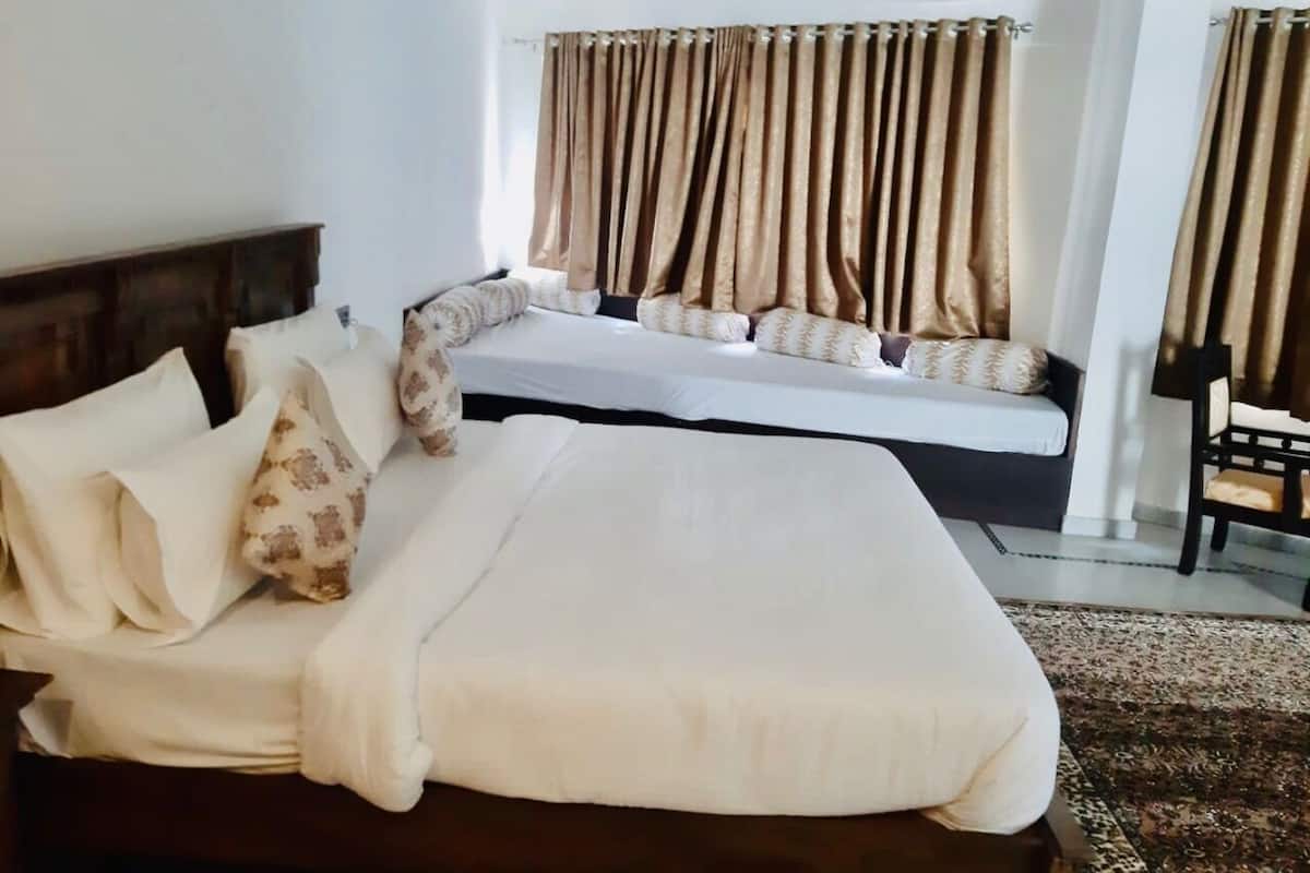 A hotel room with a large bed, a sofa bed, and a chair.