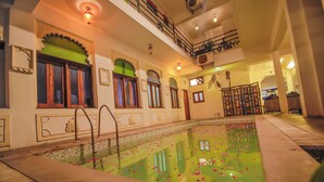Una piscina interior con arcos decorativos y un balcón con vistas a la zona de la piscina.