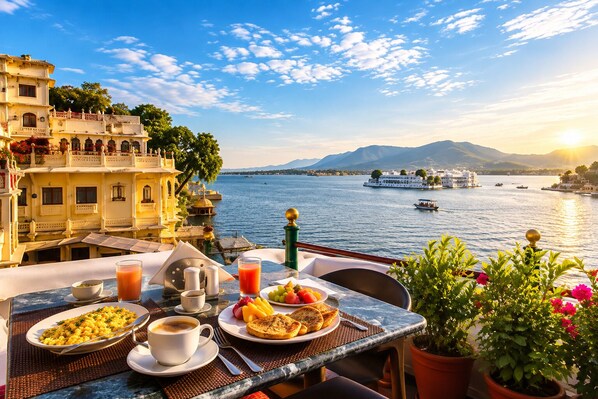 Una mesa con alimentos para el desayuno, vista a un lago con barcos y arquitectura tradicional.