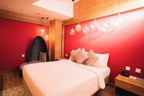 A room with a bed, a chair, a nightstand, and a wall-mounted lamp. - The Orchard Hotel Baguio (Baguio)