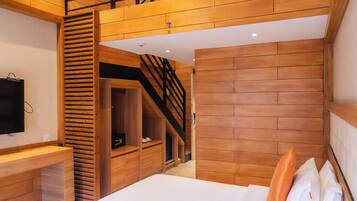 A bedroom with two beds, a TV, wooden paneling, and a staircase to an upper level.