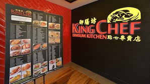 A menu board with various dim sum dishes and a neon sign for King Chef Dim Sum Kitchen.