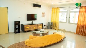 A modern living room with a sofa, a coffee table, a TV, and a small cabinet. - Villa De l'Intégration (Ouagadougou)