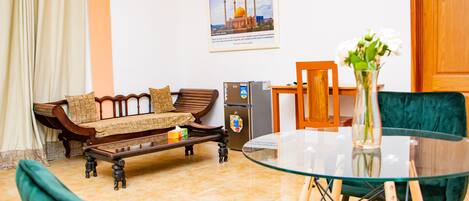 A living room with a sofa, a glass table, and a decorative vase.