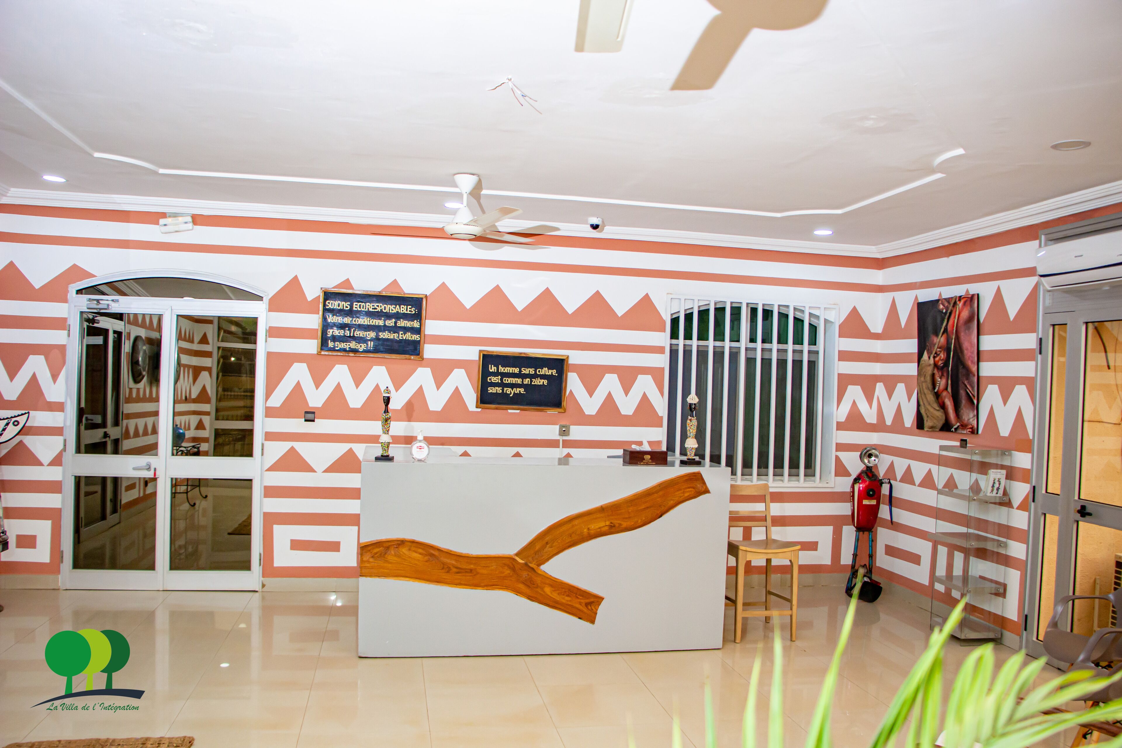 A reception area with a modern design, featuring a large wooden sculpture, a reception desk, and a signboard.