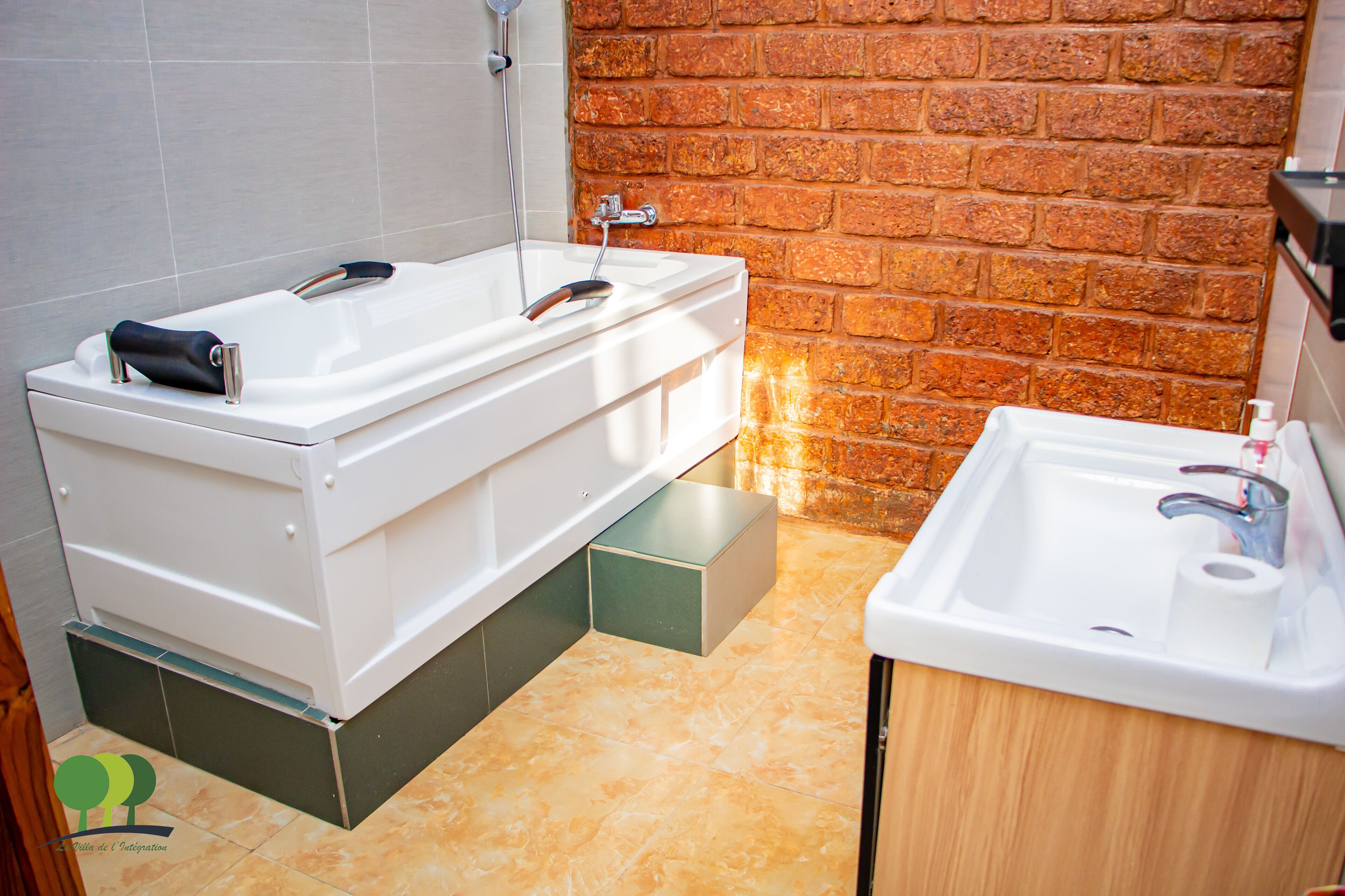 A bathroom with a bathtub, a sink, and a brick wall.