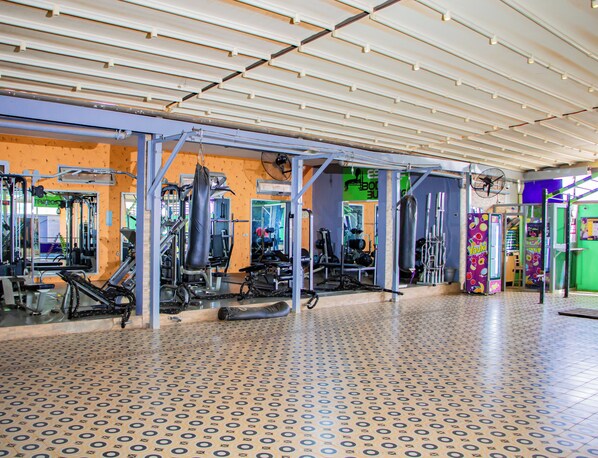 A gym with various exercise equipment, a patterned floor, and a ceiling with exposed beams. - Villa De l'Intégration (Ouagadougou)
