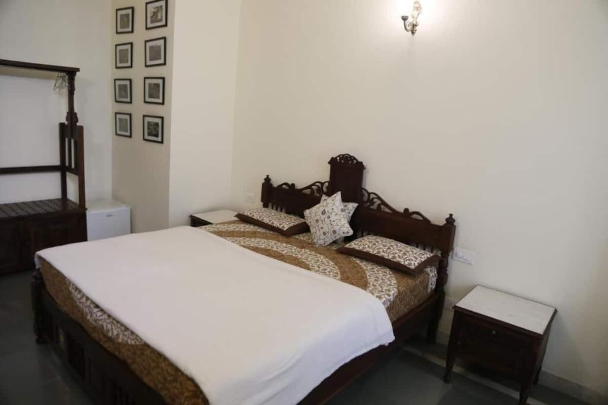 Ein Schlafzimmer mit einem großen Bett, einem Nachttisch, einer Wandleuchte und mehreren gerahmten Bildern.