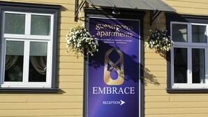 A building with a reception sign for 'Embrace' guesthouses and apartments. - Embrace Guestrooms & Apartments (Parnu)