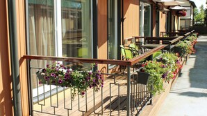 A wooden deck with outdoor seating, potted plants, and a railing. - Embrace Guestrooms & Apartments (Parnu)
