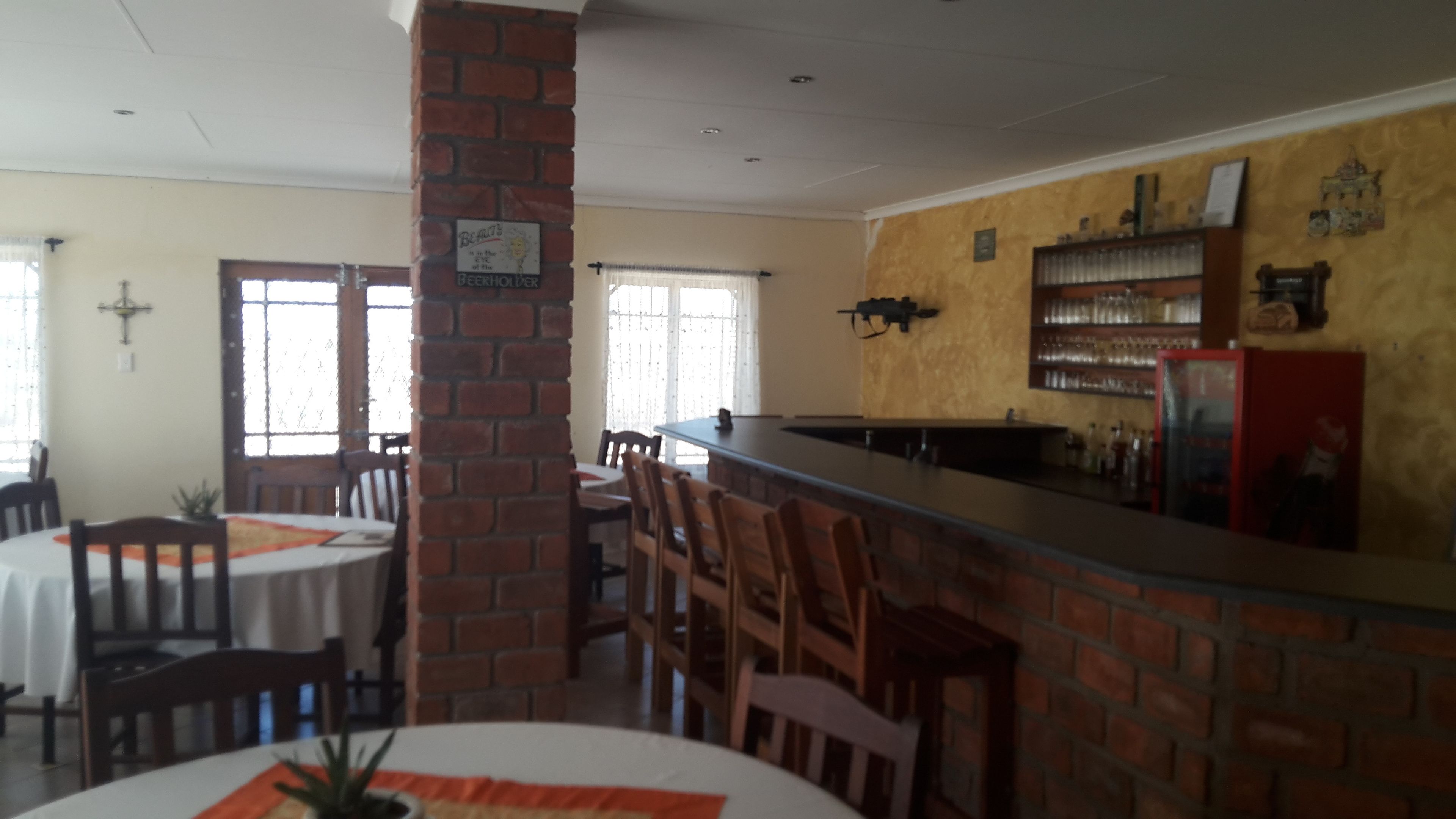 A restaurant with brick walls, a bar area, and a dining section with tables and chairs.