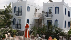 Een wit gebouw met blauwe accenten, balkons en terras met parasols.