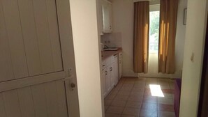 Een keuken met witte kastjes, een aanrecht en een raam met gordijnen.