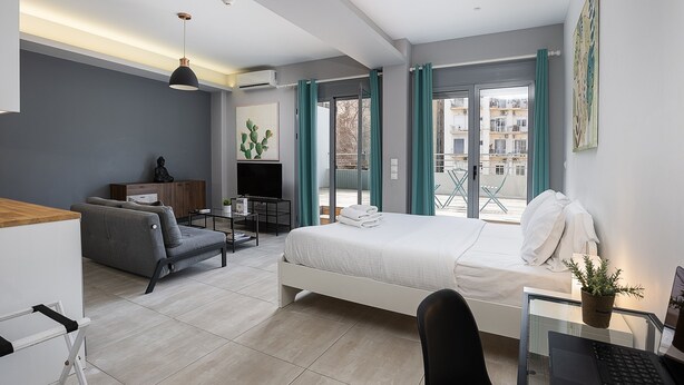 A modern hotel room with a bed, desk, and seating area. - The Omnia Collection Pagrati (Athens)