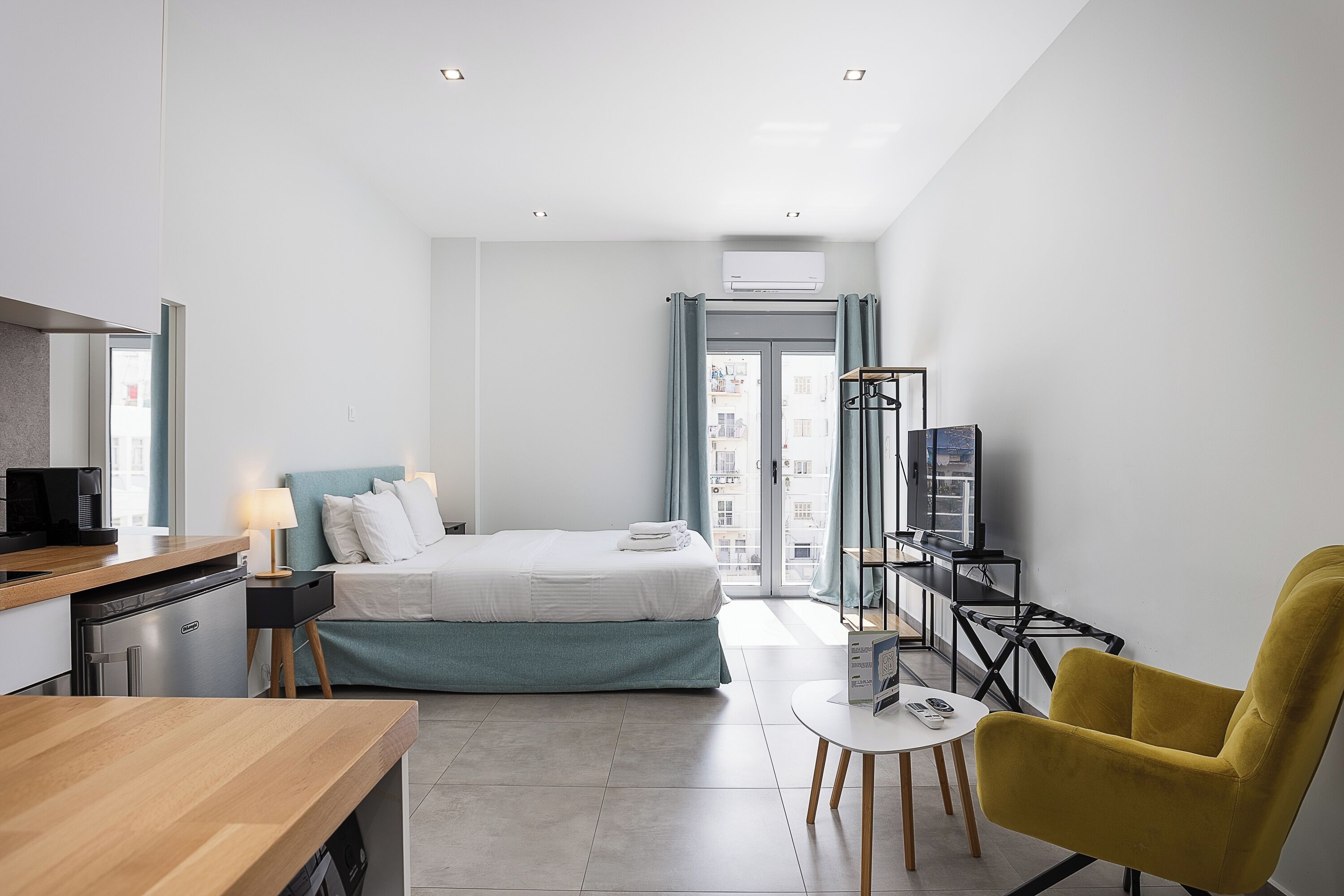 A modern hotel room with a bed, a desk, a chair, and a television.