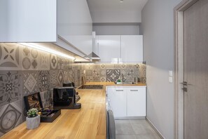 A modern kitchen with patterned tiles, a wooden countertop, and white cabinetry. - The Omnia Collection Pagrati (Athens)