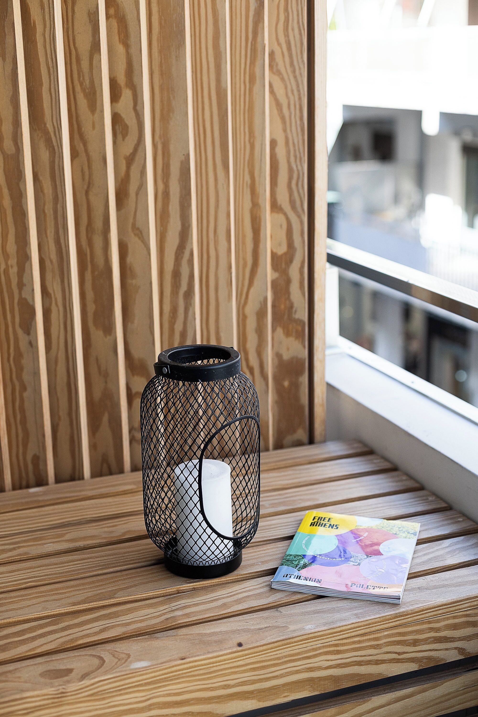 Un banc en bois, une lanterne en métal et un magazine.