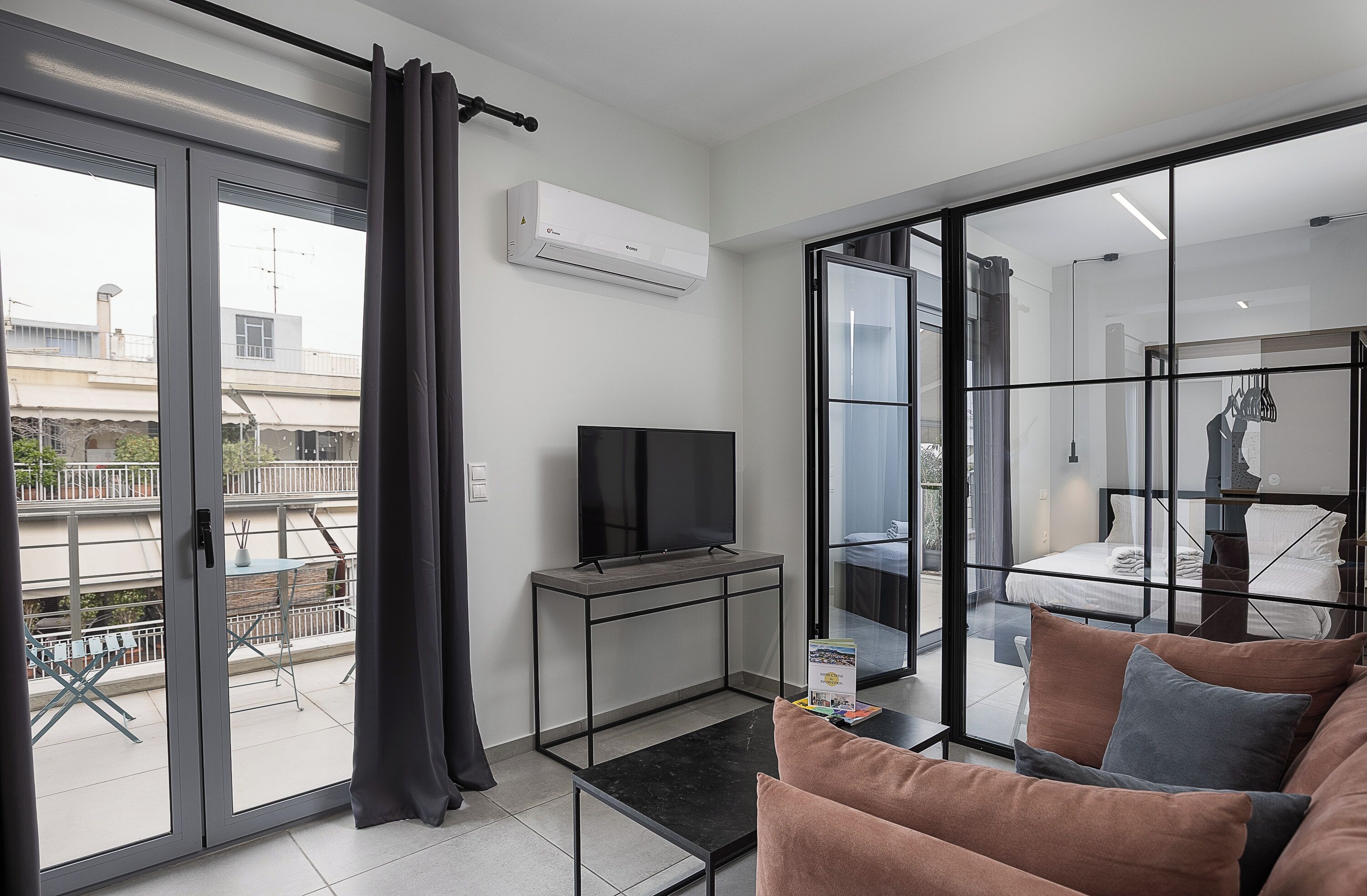 A modern living room with a TV, sofa, and a balcony with a table and chairs.