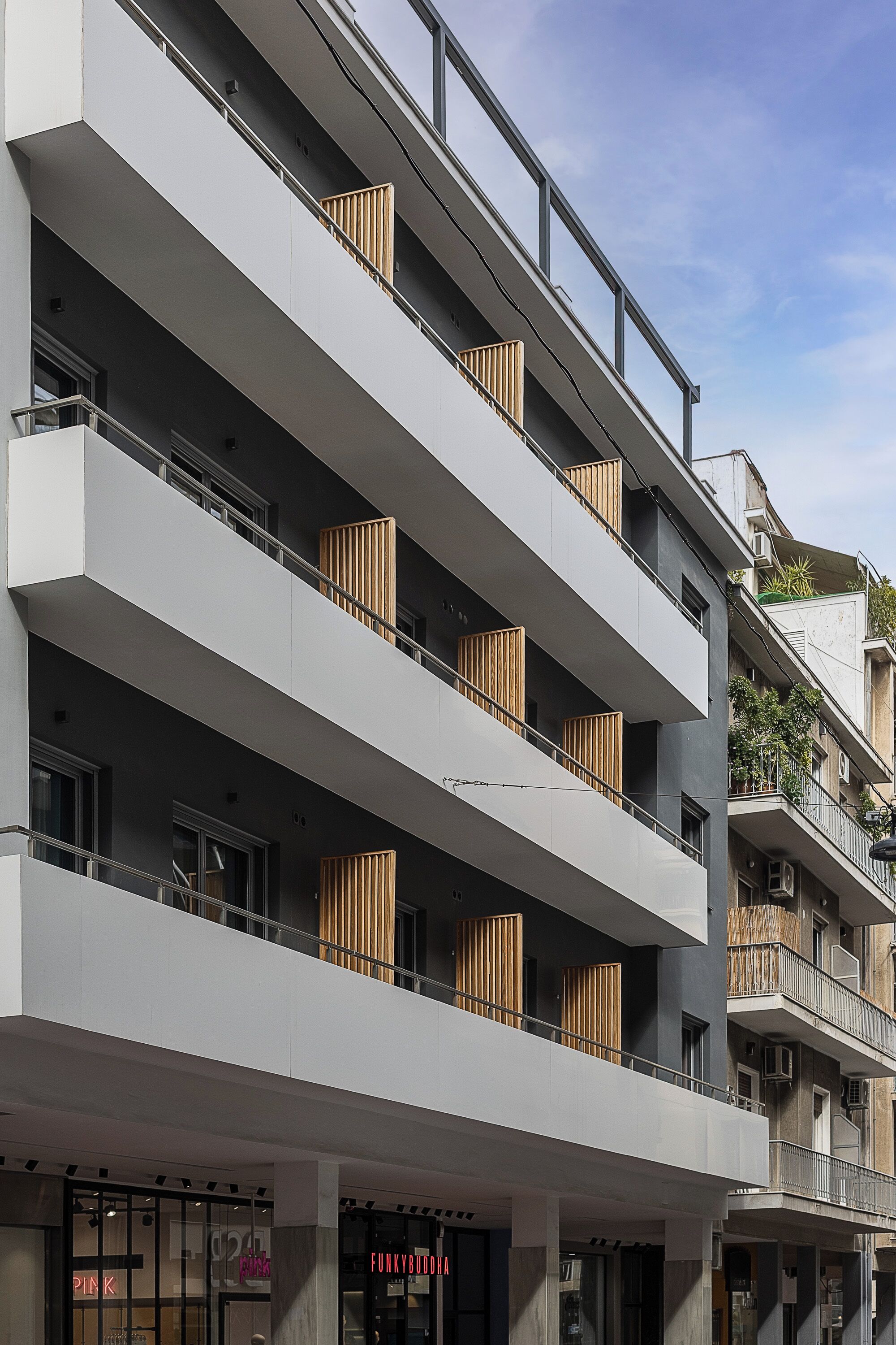 Un immeuble à plusieurs étages doté de balcons, de grandes fenêtres et d’une devanture avec une enseigne.