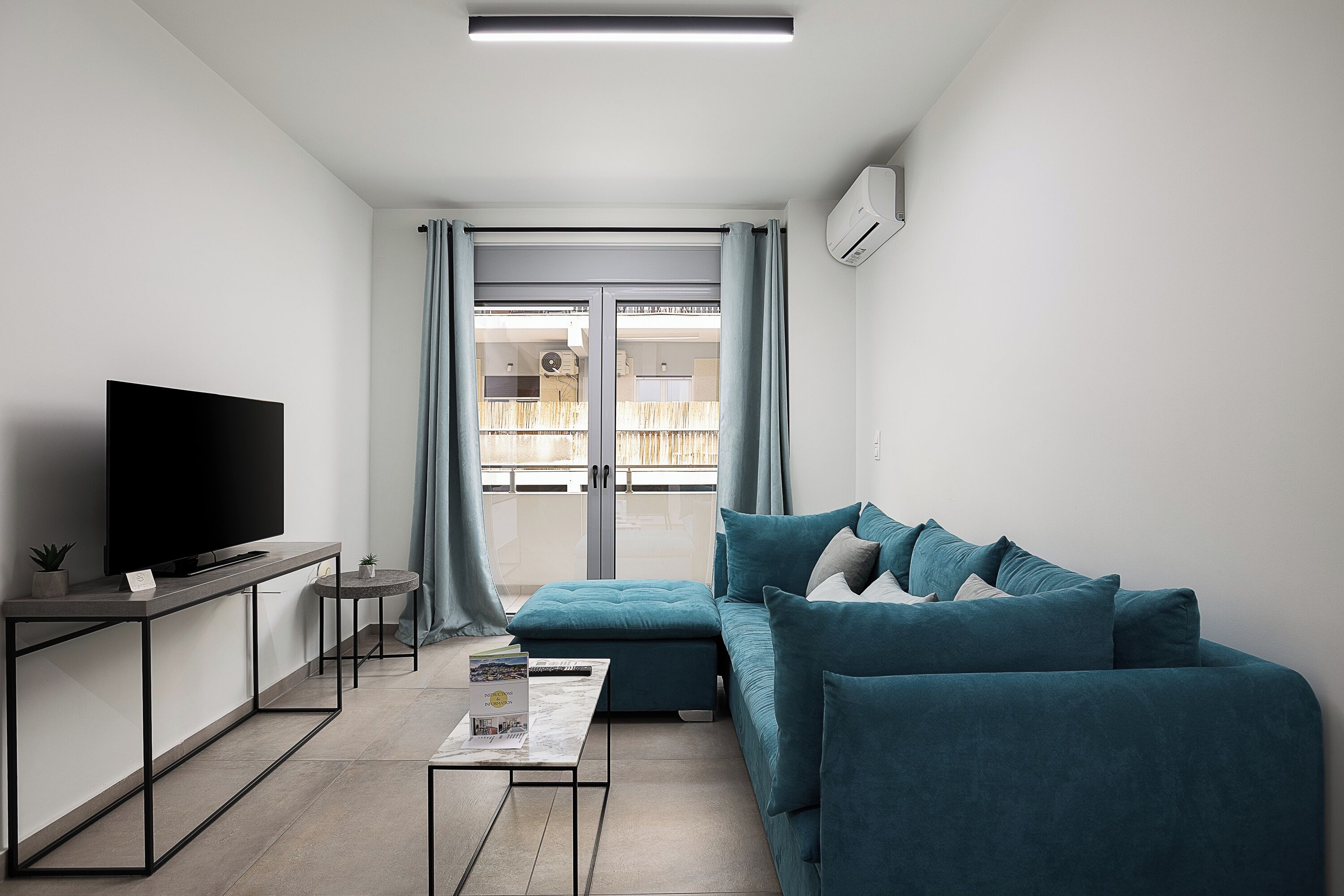 A modern living room with a flat-screen TV, a sofa, a coffee table, and a small side table.