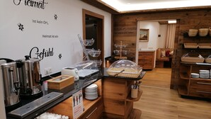 A breakfast buffet area with stainless steel appliances, a wooden counter, and a sign indicating the location. - Scheulinghof (Mayrhofen)