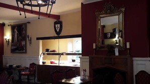 Un coin repas agrémenté d’un lustre, d’une cheminée et d’un miroir mural.