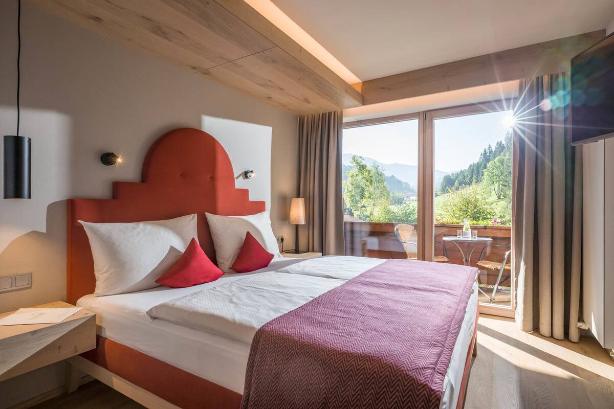 Habitación de hotel con una cama grande, un escritorio y vistas al exterior.