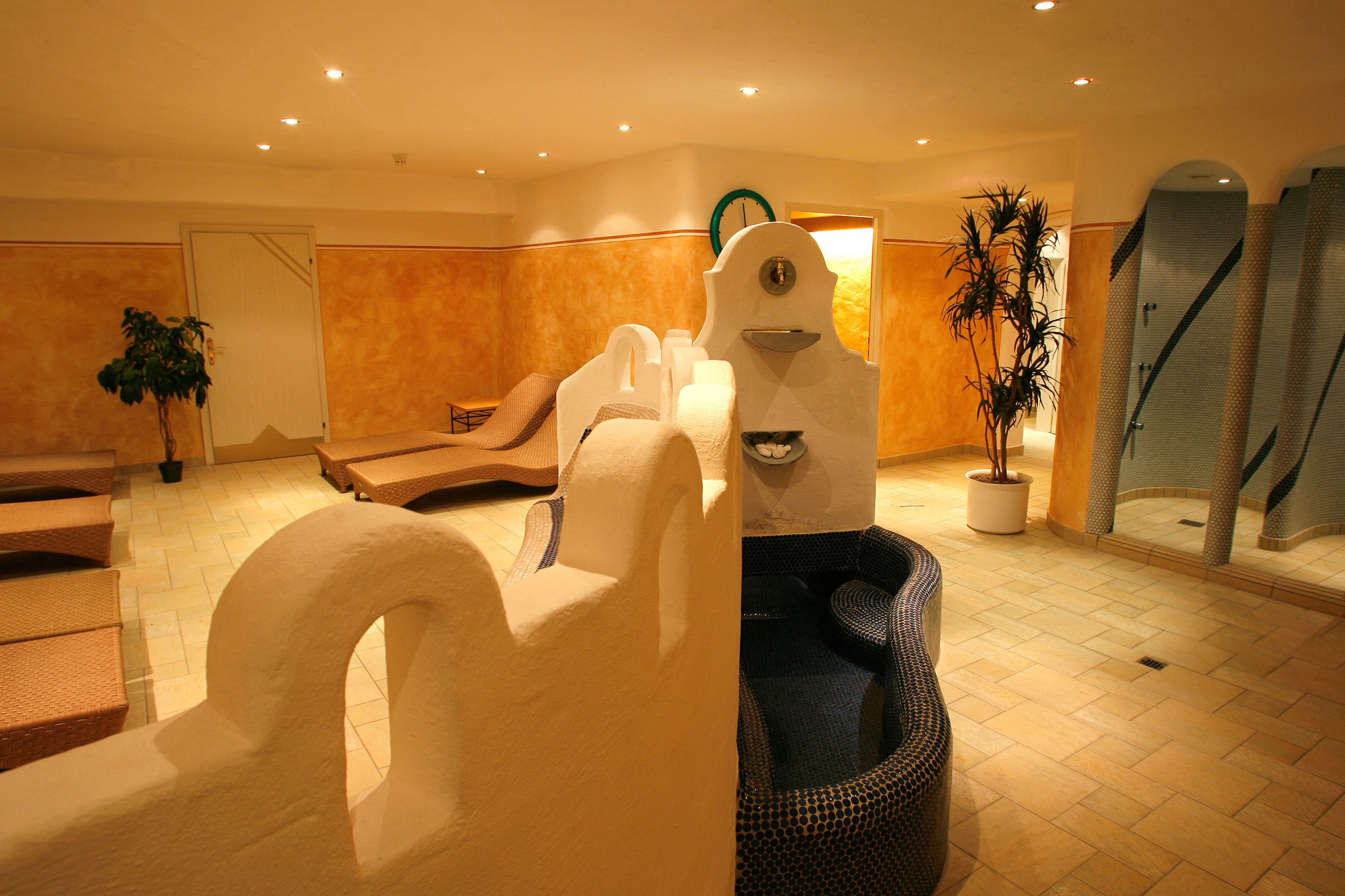 A spa-like room with a large white sculpture, a blue patterned chair, and a potted plant.